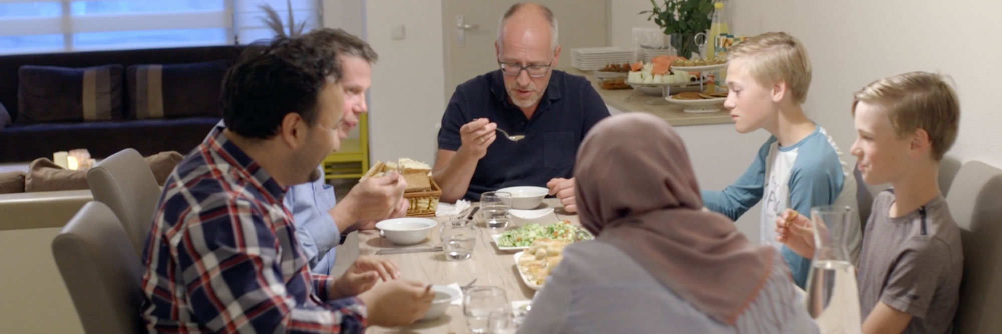 Buurtbewoners eten samen aan tafel